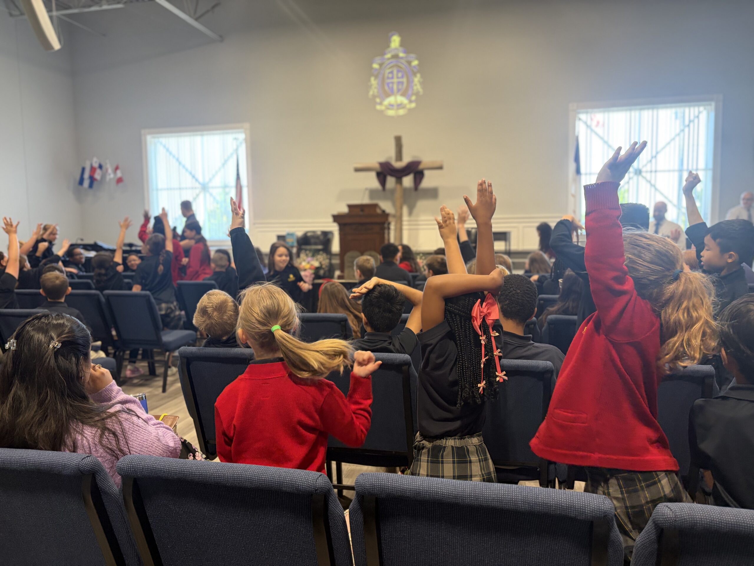 Fishers Christian Academy students raising their hands in the auditorium